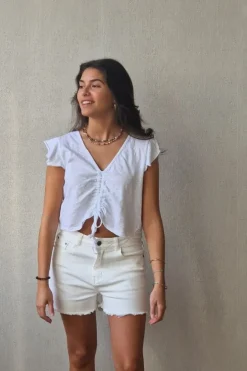 Camiseta blanca con volantes en los hombros y frunce en el pecho