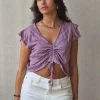 Camiseta lila con volantes en los hombros y frunce en el pecho
