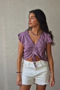Camiseta lila con volantes en los hombros y frunce en el pecho