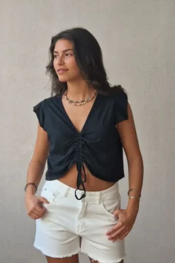 Camiseta negra con volantes en los hombros y frunce en el pecho